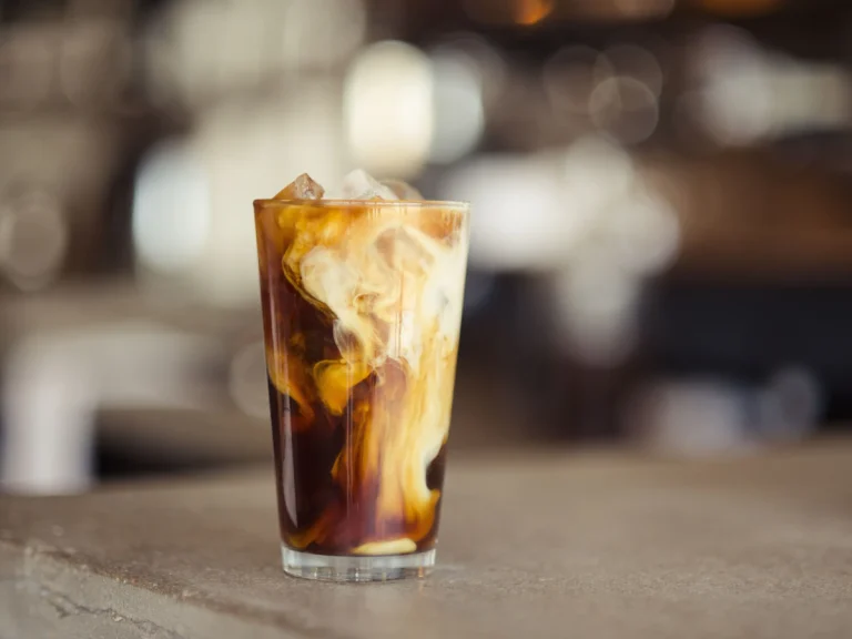 Iced latte with milk swirling into cold coffee