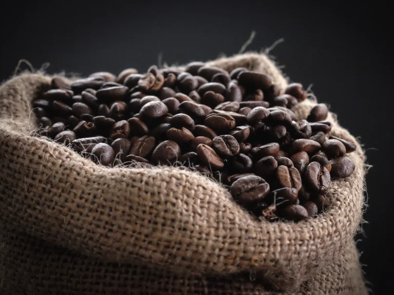 Whole coffee beans spilling from a burlap bag